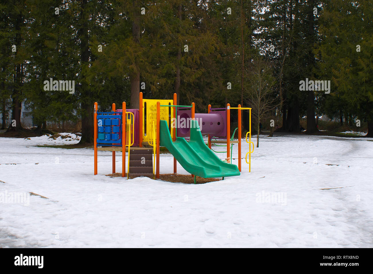 Colourful children`s play station during the winter with snow on ground. Stock Photo